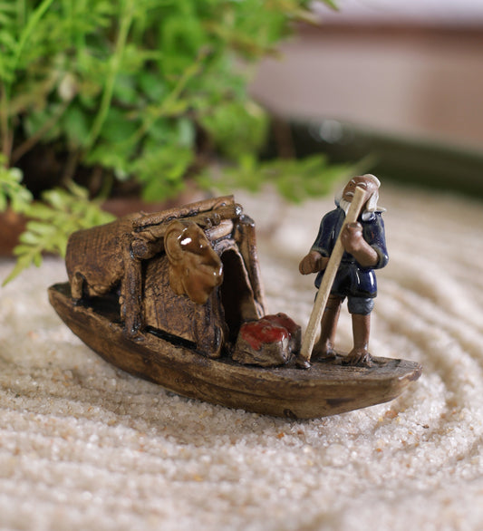 Old Fisherman In Blue Standing On Boat With Stick
