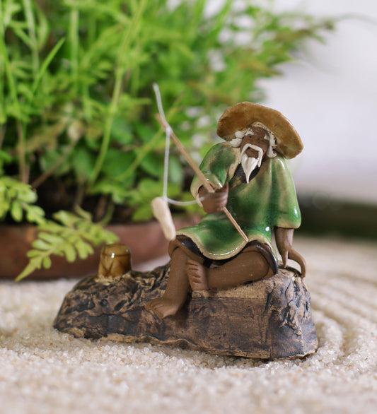 Old Fisherman In Brown With Fishing Rod On Rock
