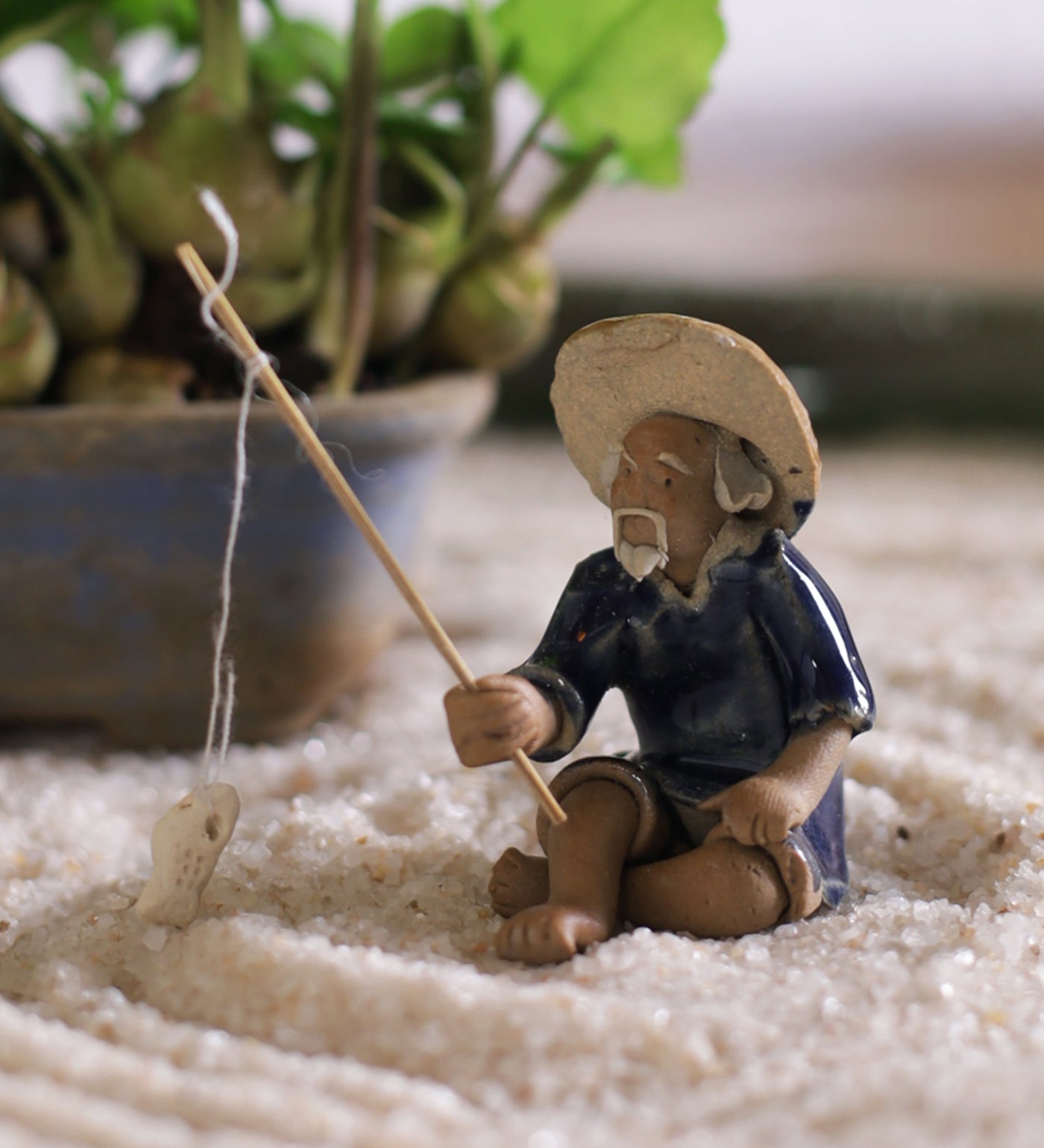 Old fisherman in blue on ground with fishing rod – Gaia Pottery In